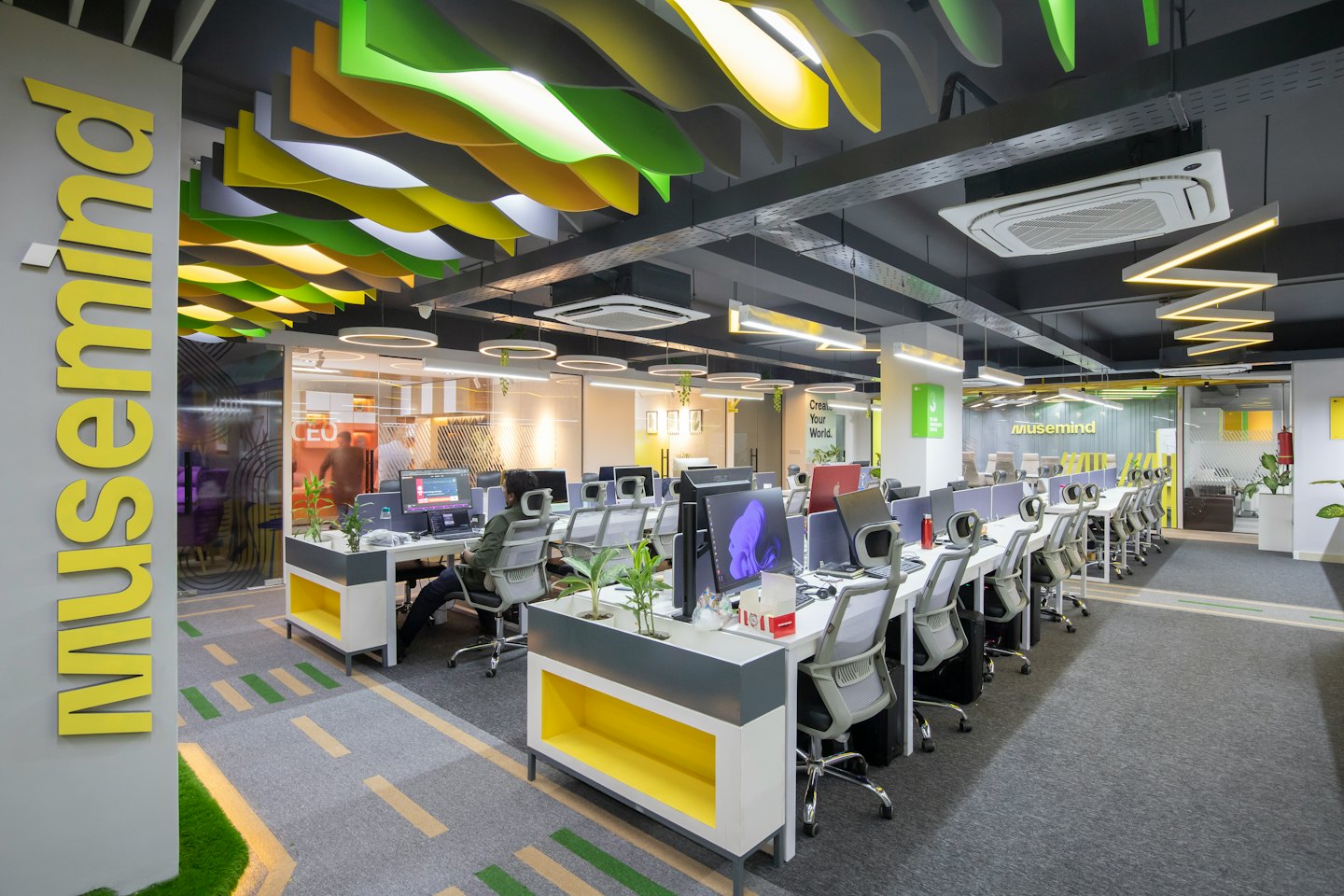 Personas trabajando en una oficina moderna de planta abierta con paneles acústicos.