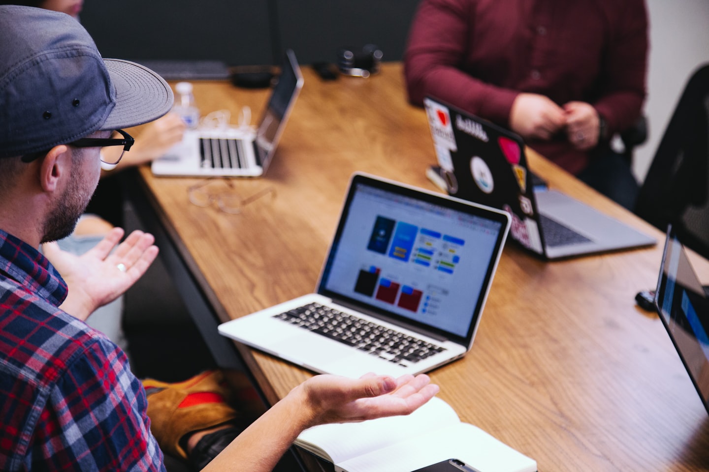 Equipo colaborando alrededor de una mesa de conferencias con gráficos en una laptop.