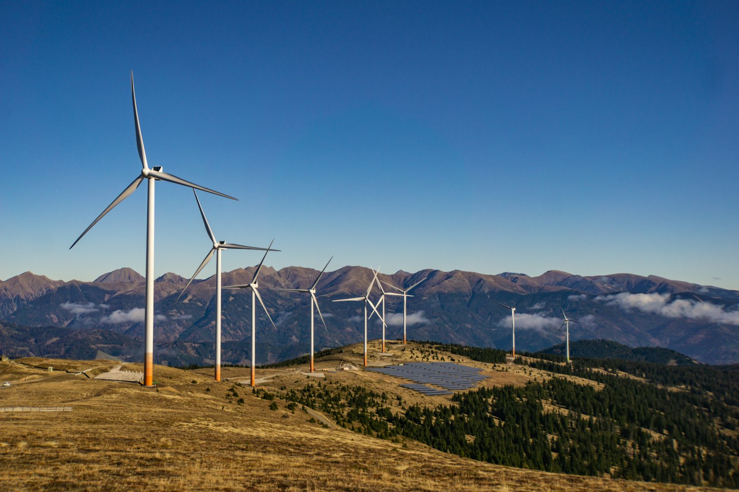 Aerogeneradores y paneles solares en una cresta montañosa cubierta de hierba.
