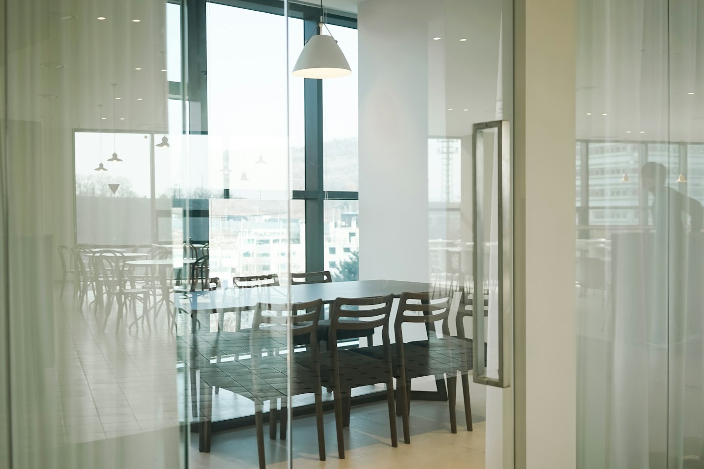 Sala de reuniones moderna con mesas de madera y paredes de cristal.