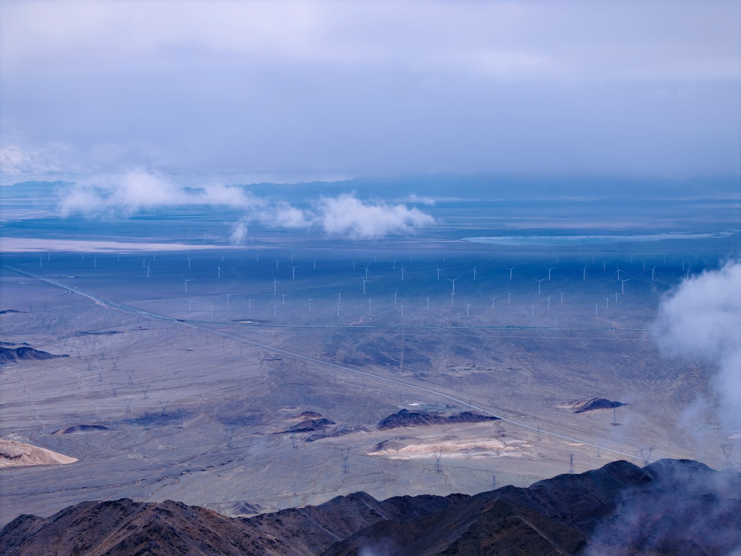 Aerogeneradores se alzan en un vasto paisaje desértico con montañas.